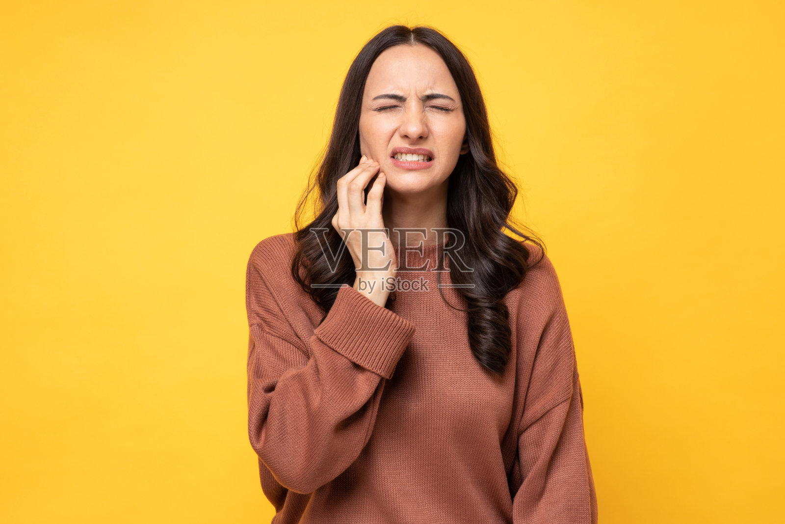 照片的年轻妇女在冬天穿站在黄色背景股票照片照片摄影图片