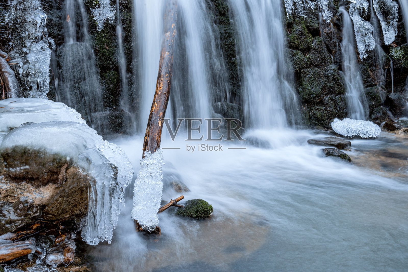 冰柱悬挂在瀑布的一侧，创造了令人惊叹的冬季景色。瀑布位于山区，岩石被冰覆盖。照片摄影图片