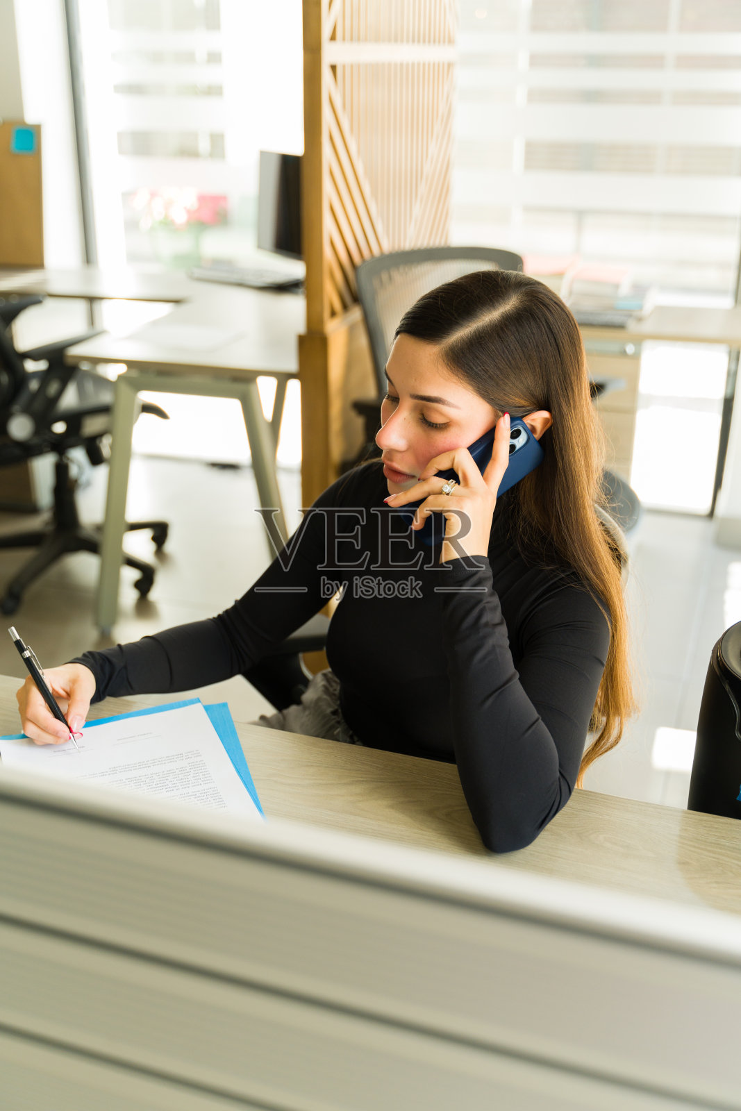 女商人在办公室里审阅合同时与客户交谈照片摄影图片