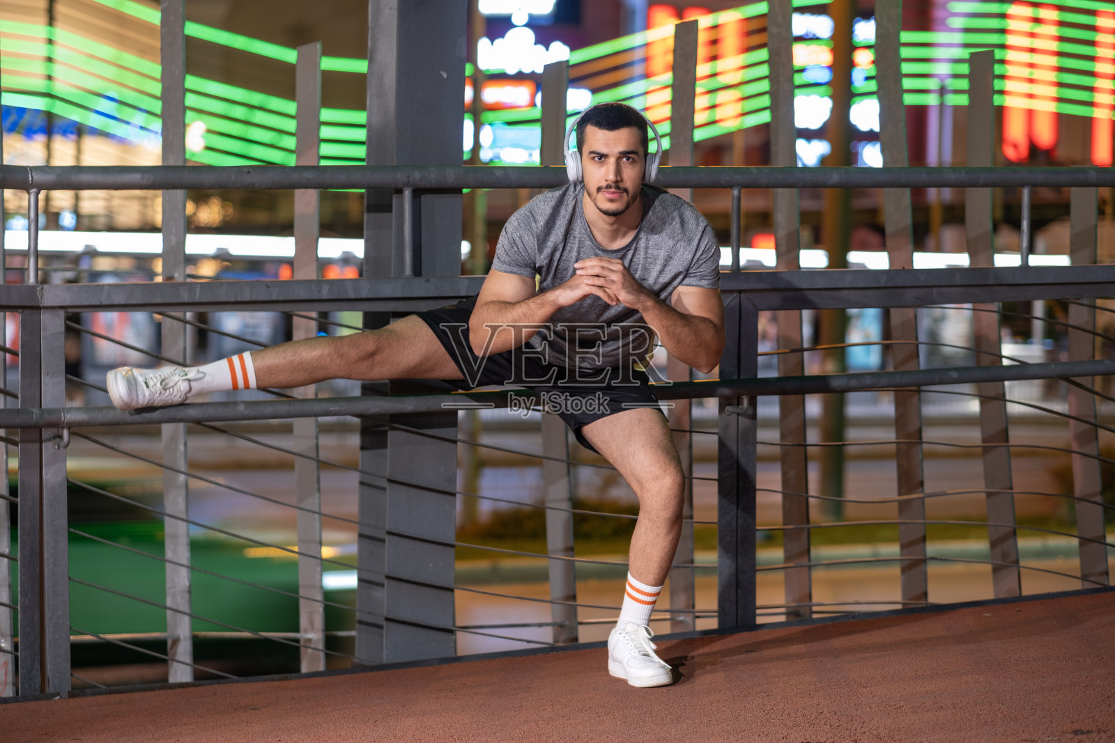 年轻人在霓虹灯的夜城里做运动，听音乐照片摄影图片