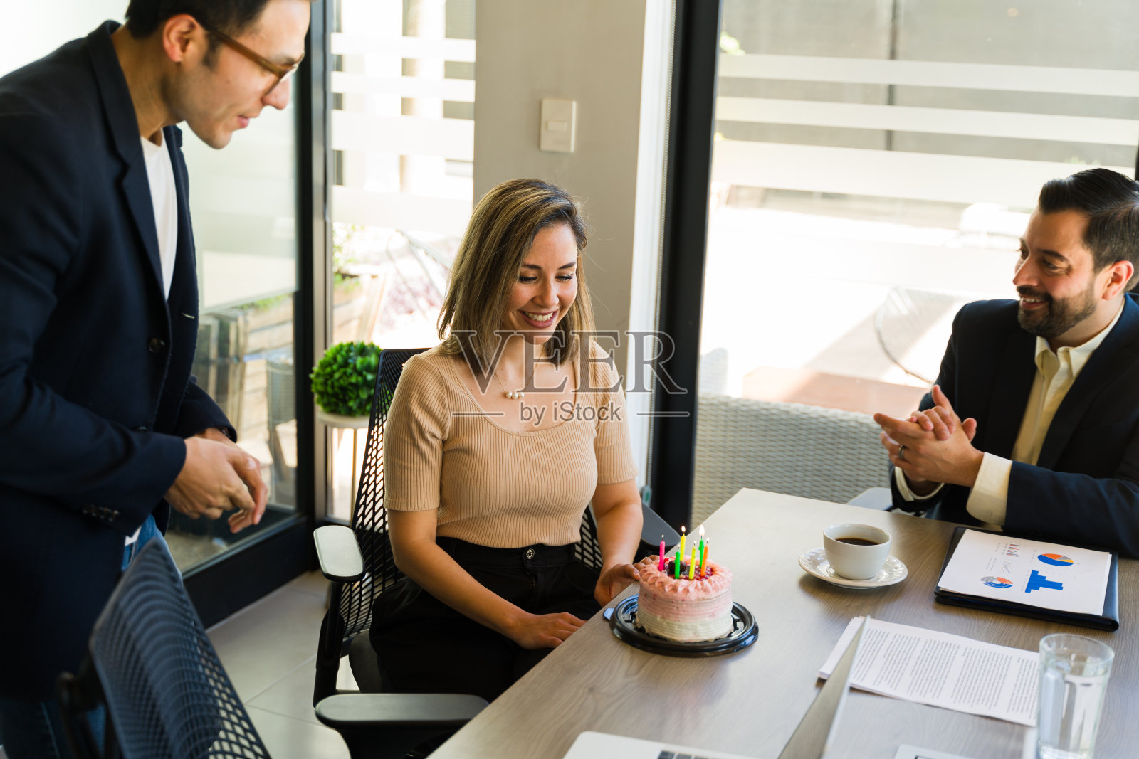 一个美丽的女人许了一个愿，看着她在办公室得到的生日蛋糕照片摄影图片