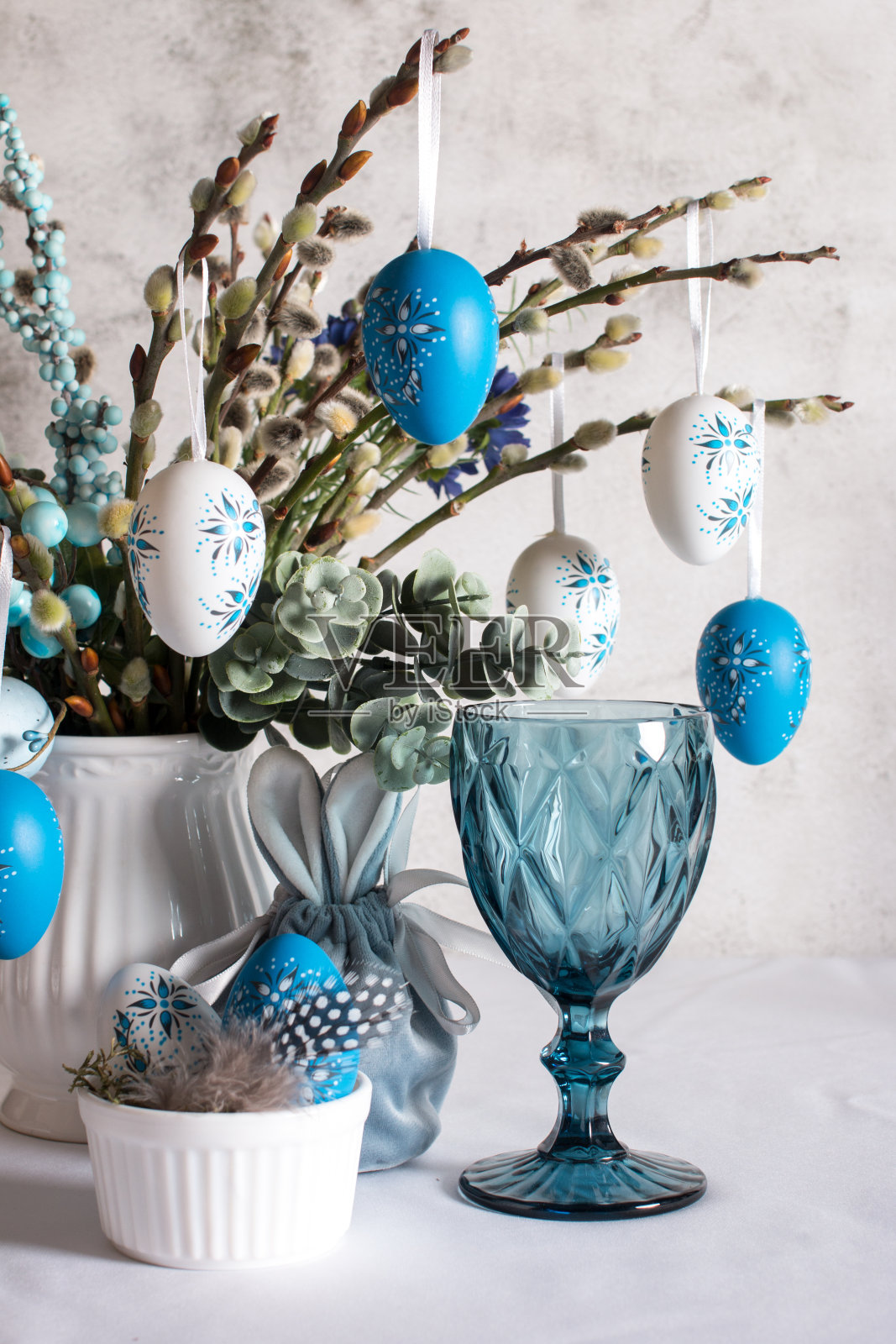 复活节餐桌布置，画彩蛋。复活节柳枝插在花瓶里的贺卡照片摄影图片