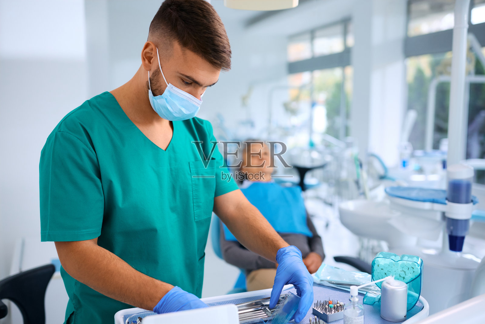 年轻的牙医正在为老年病人准备牙科检查工具。照片摄影图片