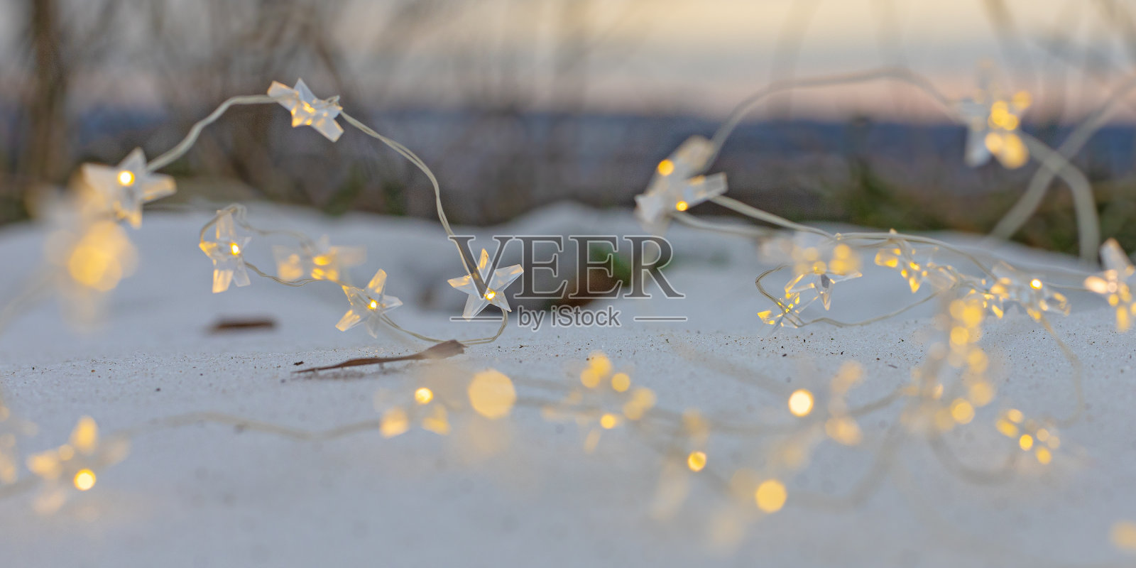 圣诞花环上的星星在冬日公园的雪地上闪闪发光照片摄影图片