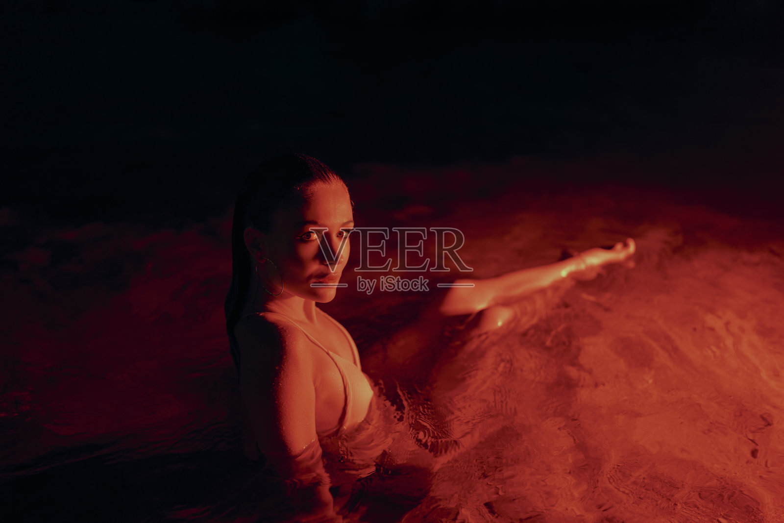 优雅的女士淹没在宁静的泻湖在夜间的时间，显示优雅，诱惑在水中。女性体现了自然之美，宁静的水环境。艺术夜间摄影。照片摄影图片