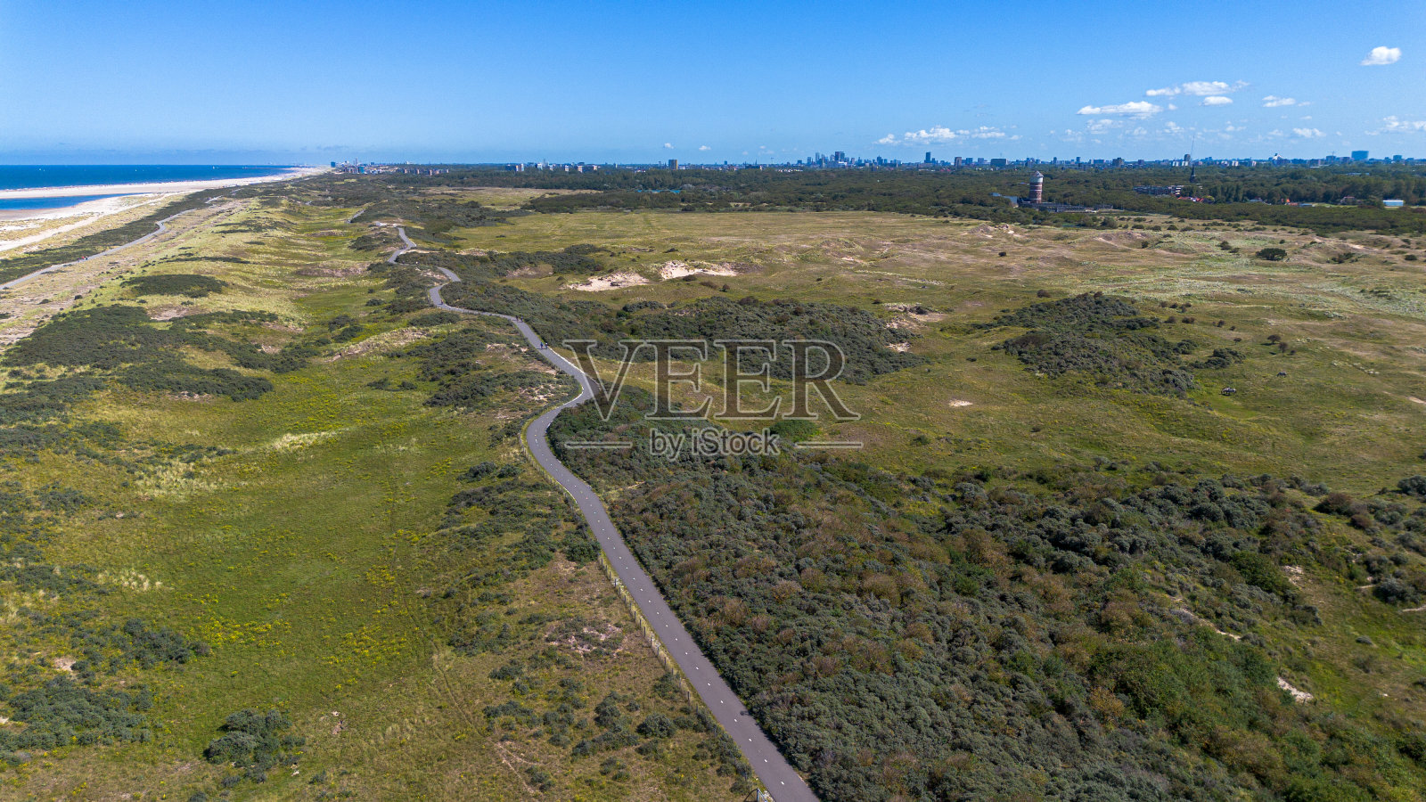海滩和大海的俯视图。飞过长满绿草的田野和海边的建筑物。背景是房子的屋顶。从北海附近的四旋翼飞机上观看照片摄影图片