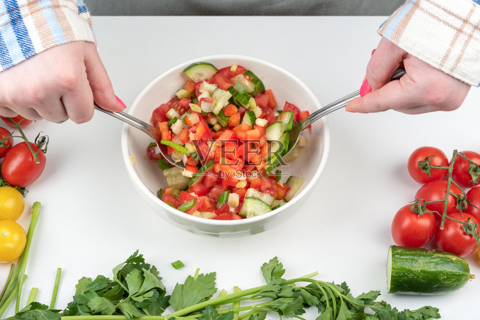 蔬菜沙拉用油调味，用勺子拌。照片摄影图片