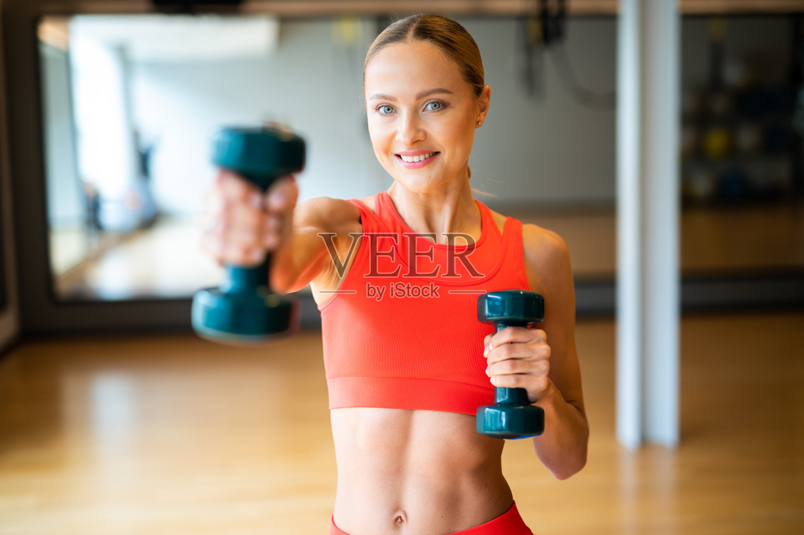 年轻漂亮的女人在健身房举哑铃照片摄影图片