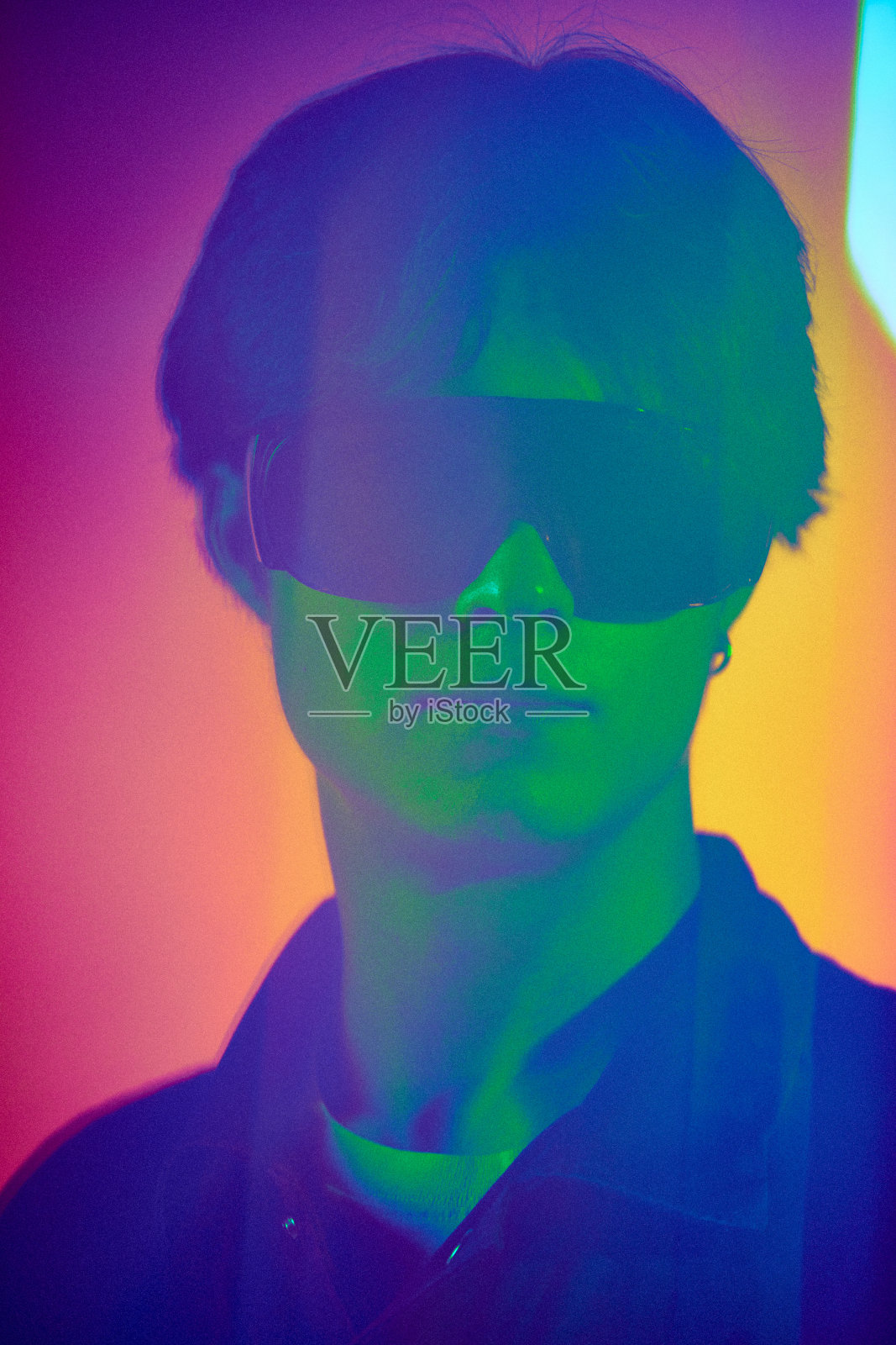 英俊的年轻人的肖像，男模特戴着时尚的防护眼镜，在霓虹灯的彩色背景下照片摄影图片