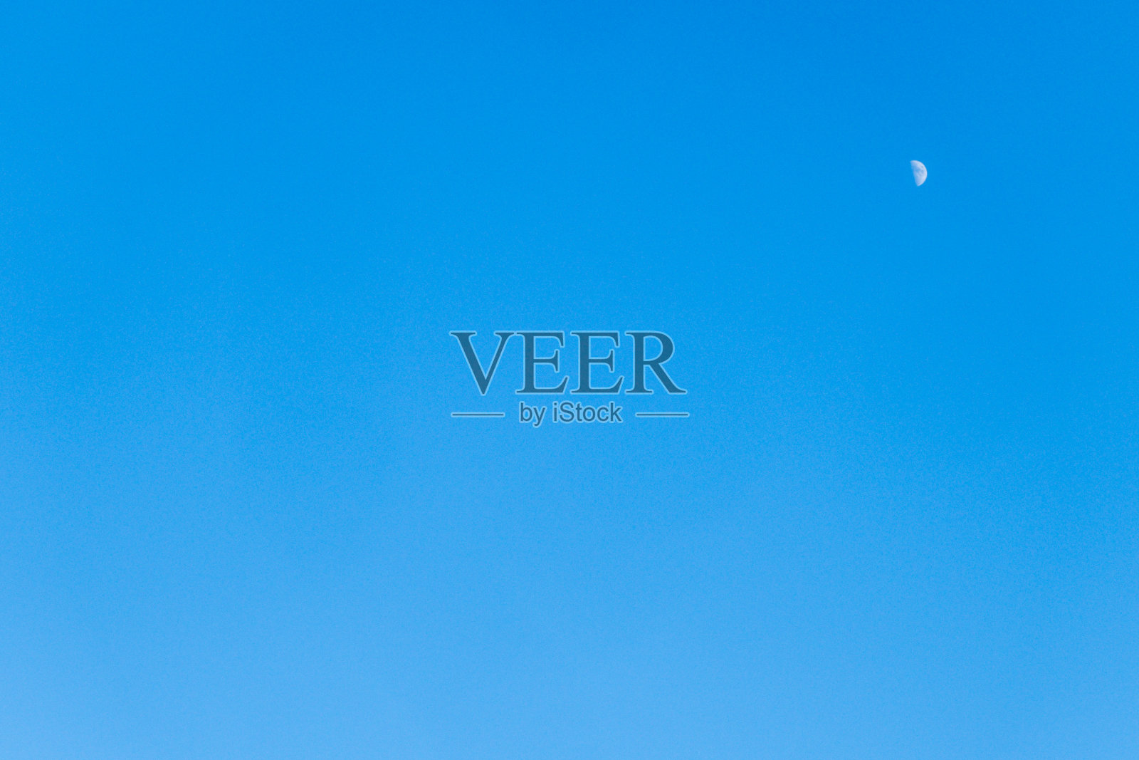 晴朗的午后天空挂着一轮小小的新月照片摄影图片