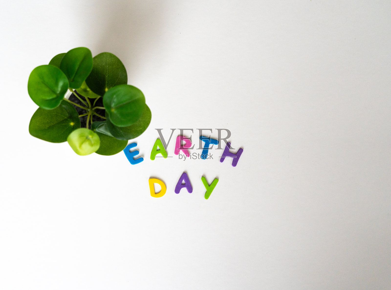 地球日用彩色的字母写在一张白色的桌子上，桌子上有一棵绿色的小植物照片摄影图片