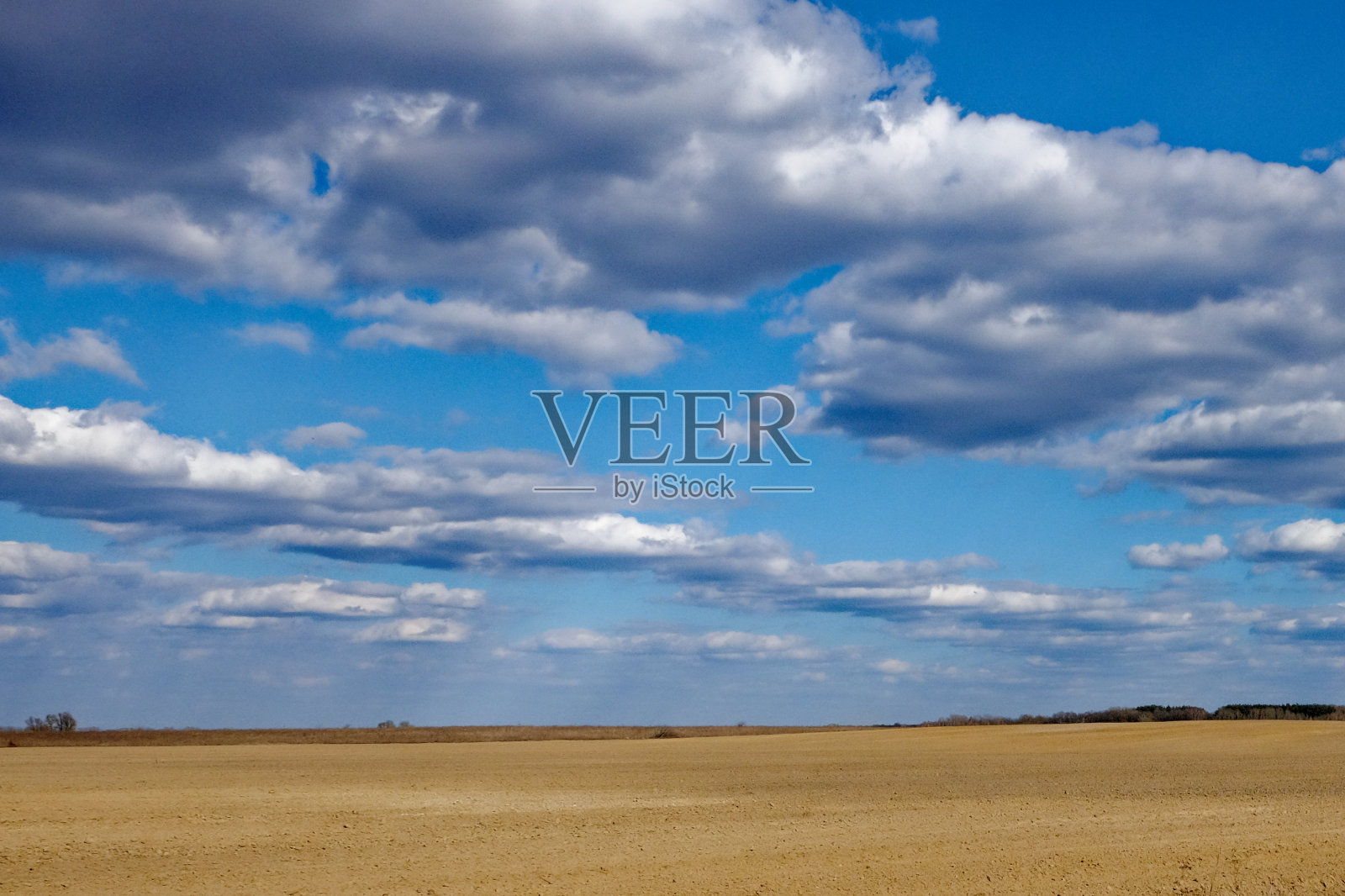 这张照片显示了多云天空下广阔的耕地。照片摄影图片