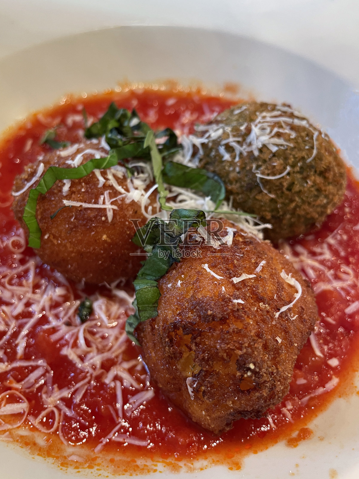 全画幅图片，白色碗里装着三个阿兰西尼饭团(米丸子)，配上番茄酱，上面撒上磨碎的帕尔马干酪，高架视图照片摄影图片