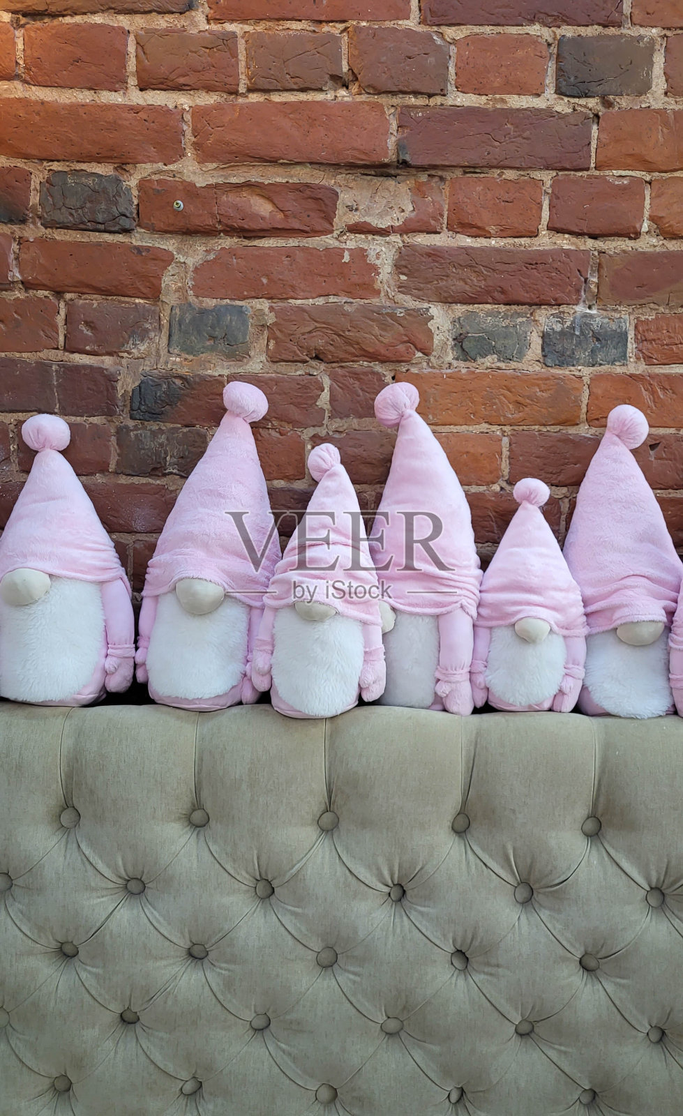 一群戴着粉色帽子、满脸胡须的可爱小矮人坐在砖墙旁照片摄影图片