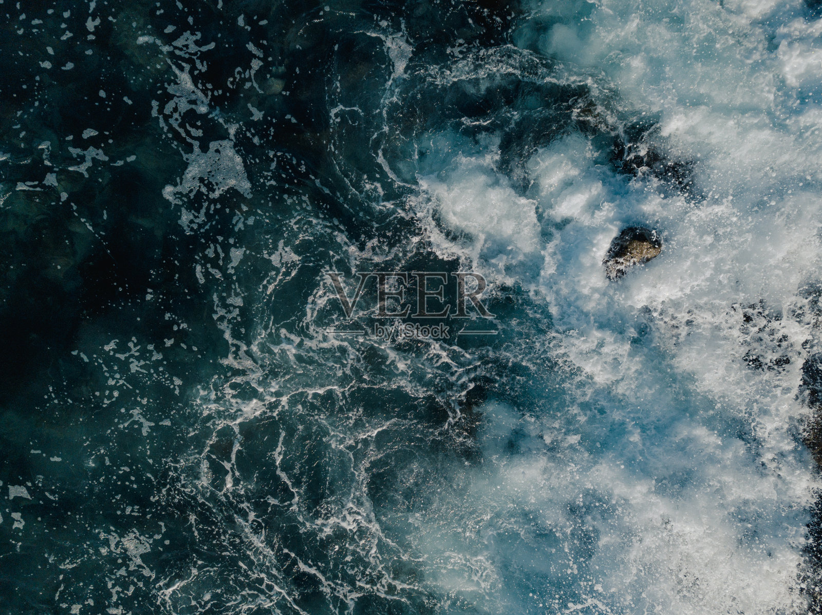 特内里费岛南部的岩石海滩，海浪拍打着火山岩海滩。你可以看到水污染，因为垃圾填埋场污染了水。照片摄影图片