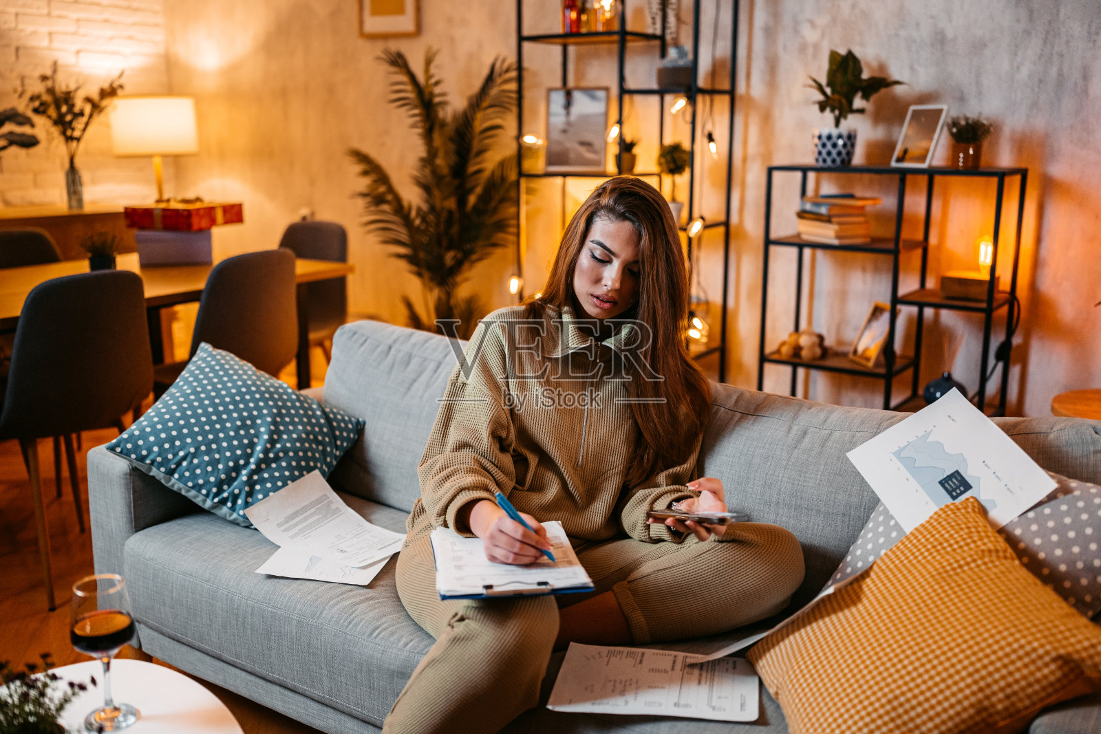 年轻女子晚上在家用手机查看自己的财务状况照片摄影图片
