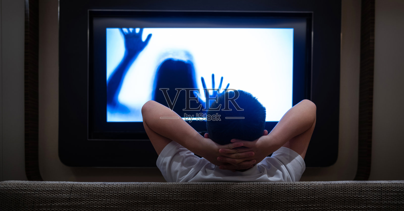 十几岁的男孩在客厅看恐怖电影照片摄影图片