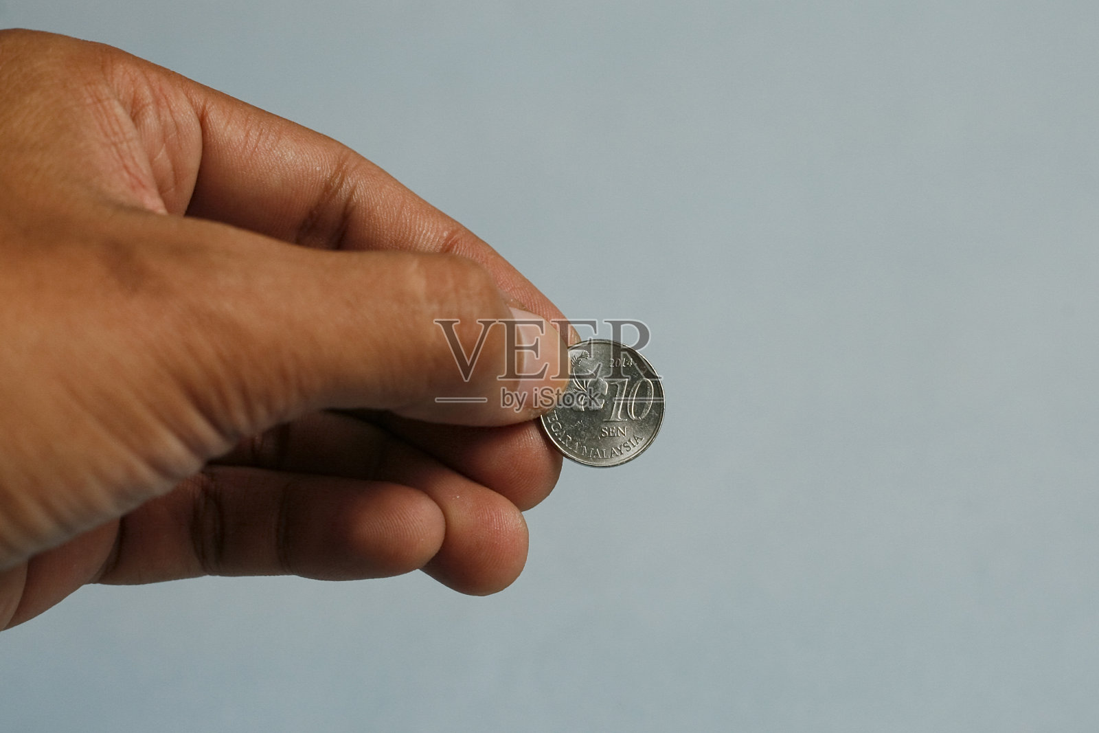 近距离手持一毛钱马来西亚硬币。慈善组织的概念。照片摄影图片