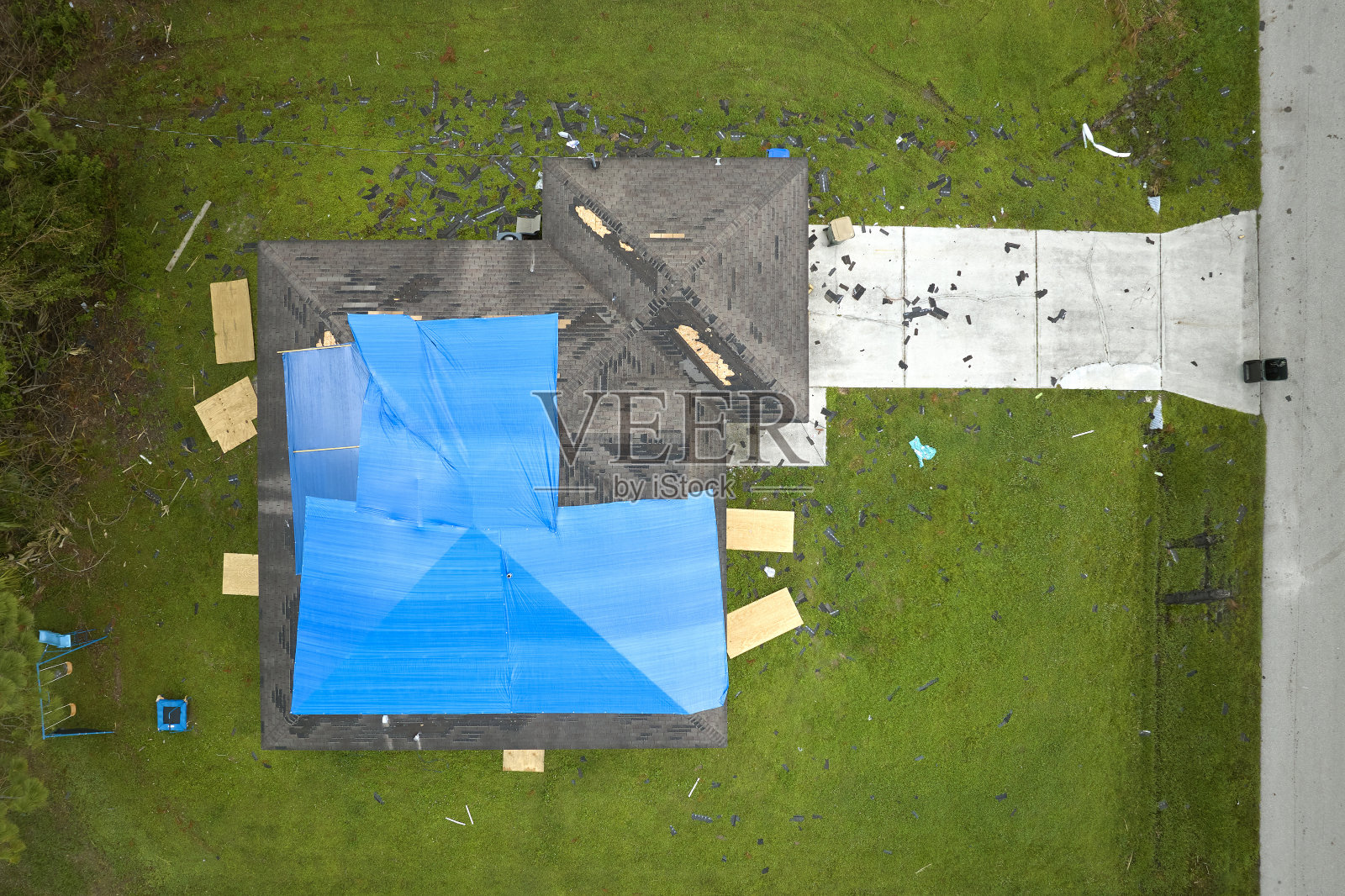 鸟瞰图，飓风伊恩损坏的屋顶覆盖着蓝色防水布防止雨水泄漏，直到更换沥青瓦照片摄影图片