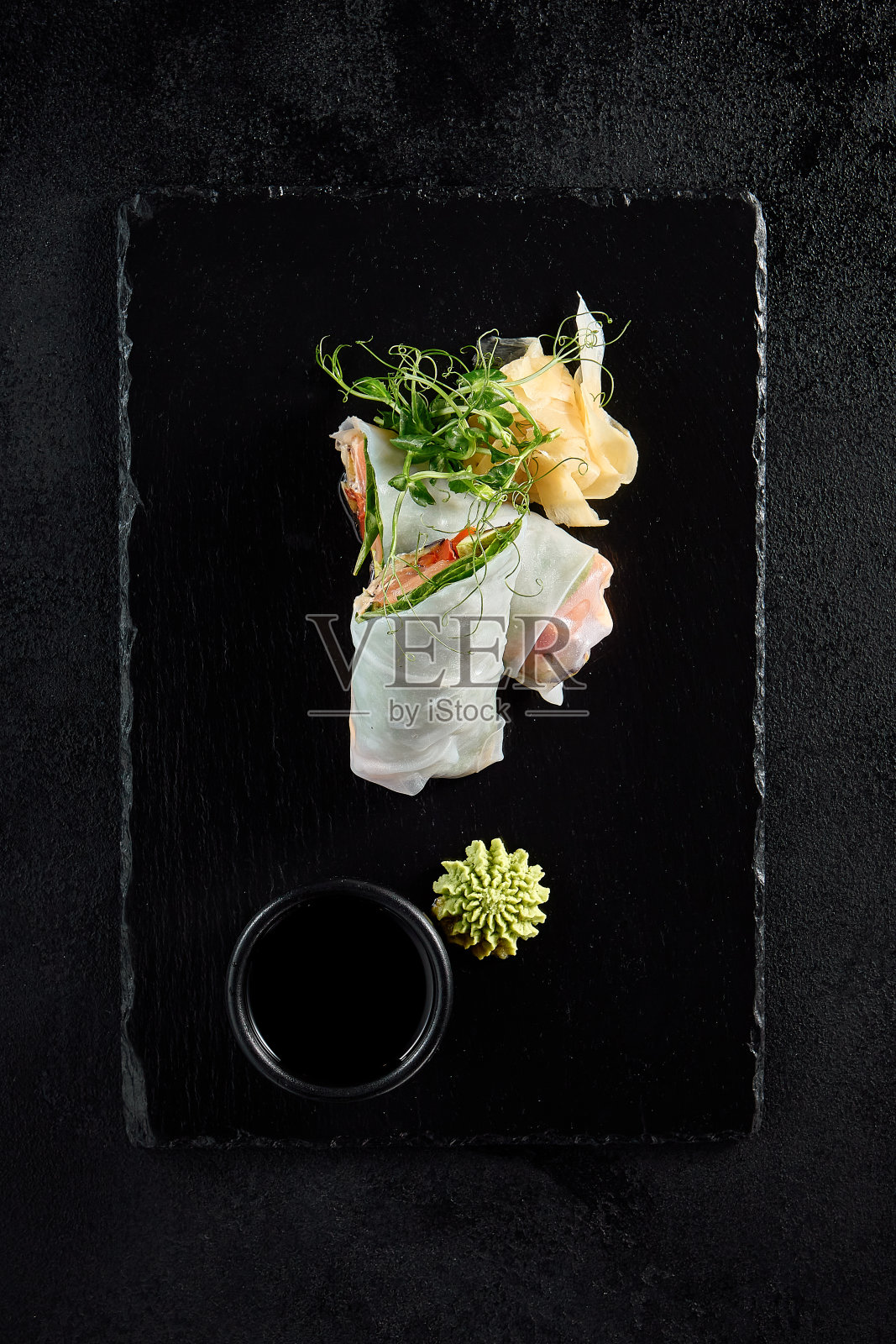 俯视图:在有纹理的黑色石板上，三文鱼和鳄梨夹心卷和绿豌豆芽照片摄影图片