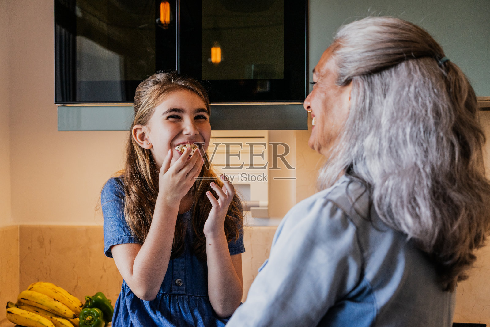 奶奶和孙女在家里的厨房里吃爆米花照片摄影图片