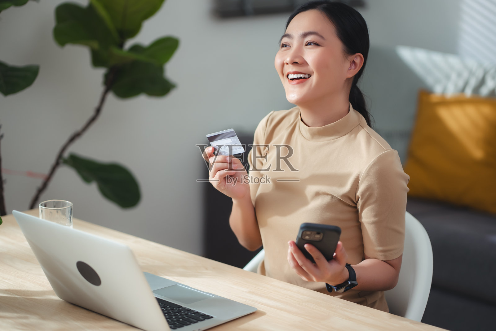亚洲女性喜欢在家里用信用卡和智能手机进行网上购物。照片摄影图片