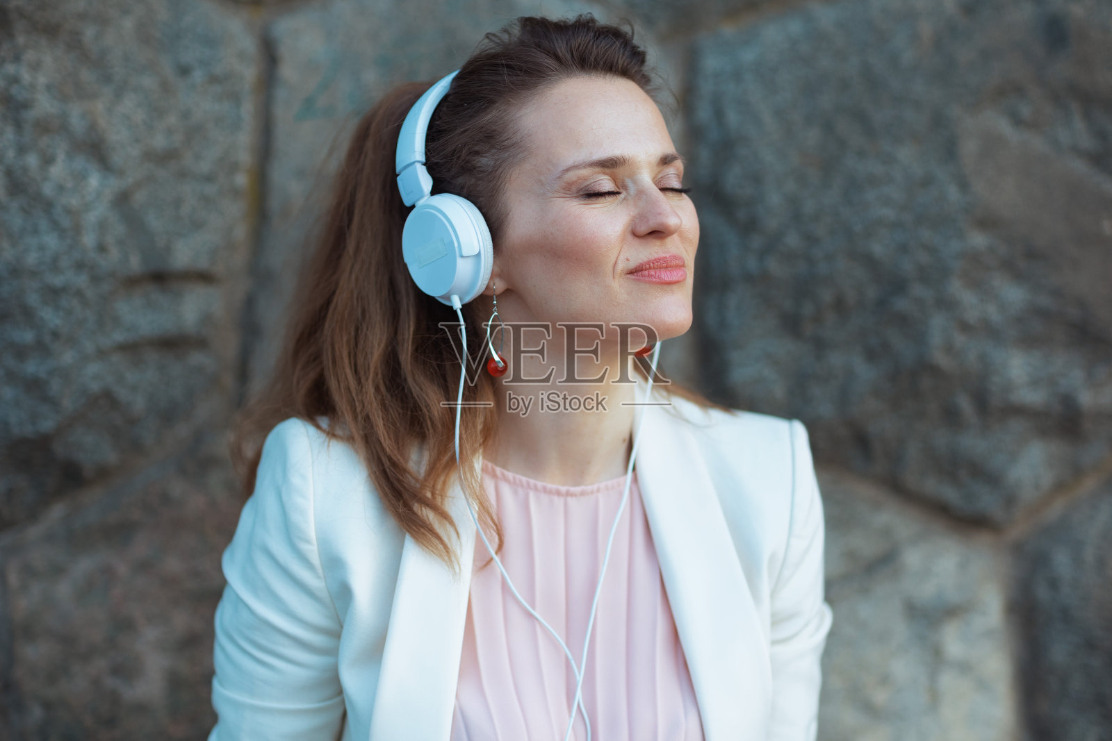 在城市里穿着粉色连衣裙和白色夹克的优雅女子照片摄影图片