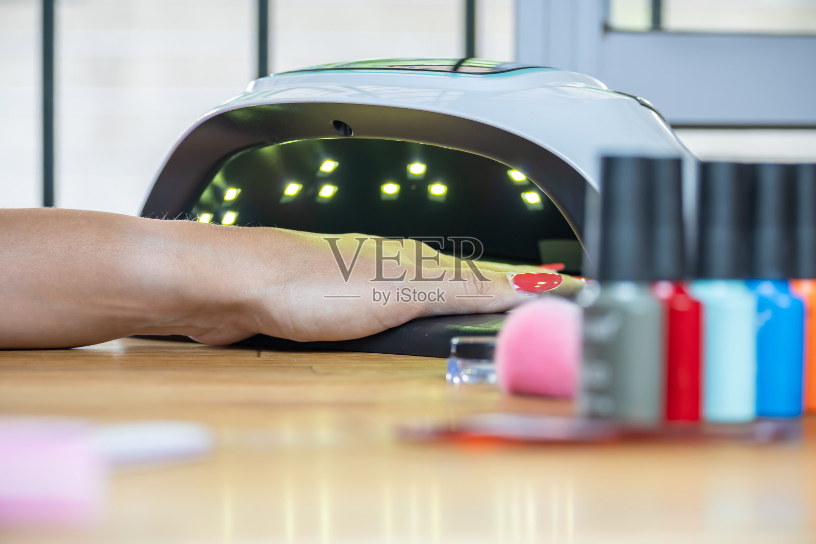 手卡在紫外线灯箱里的女人。她在等油漆干。照片摄影图片