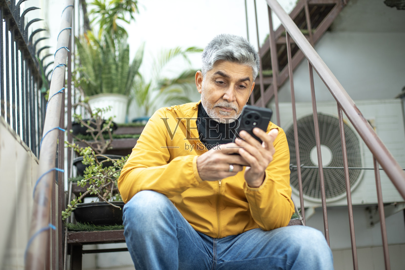 老人在台阶上用手机发短信照片摄影图片