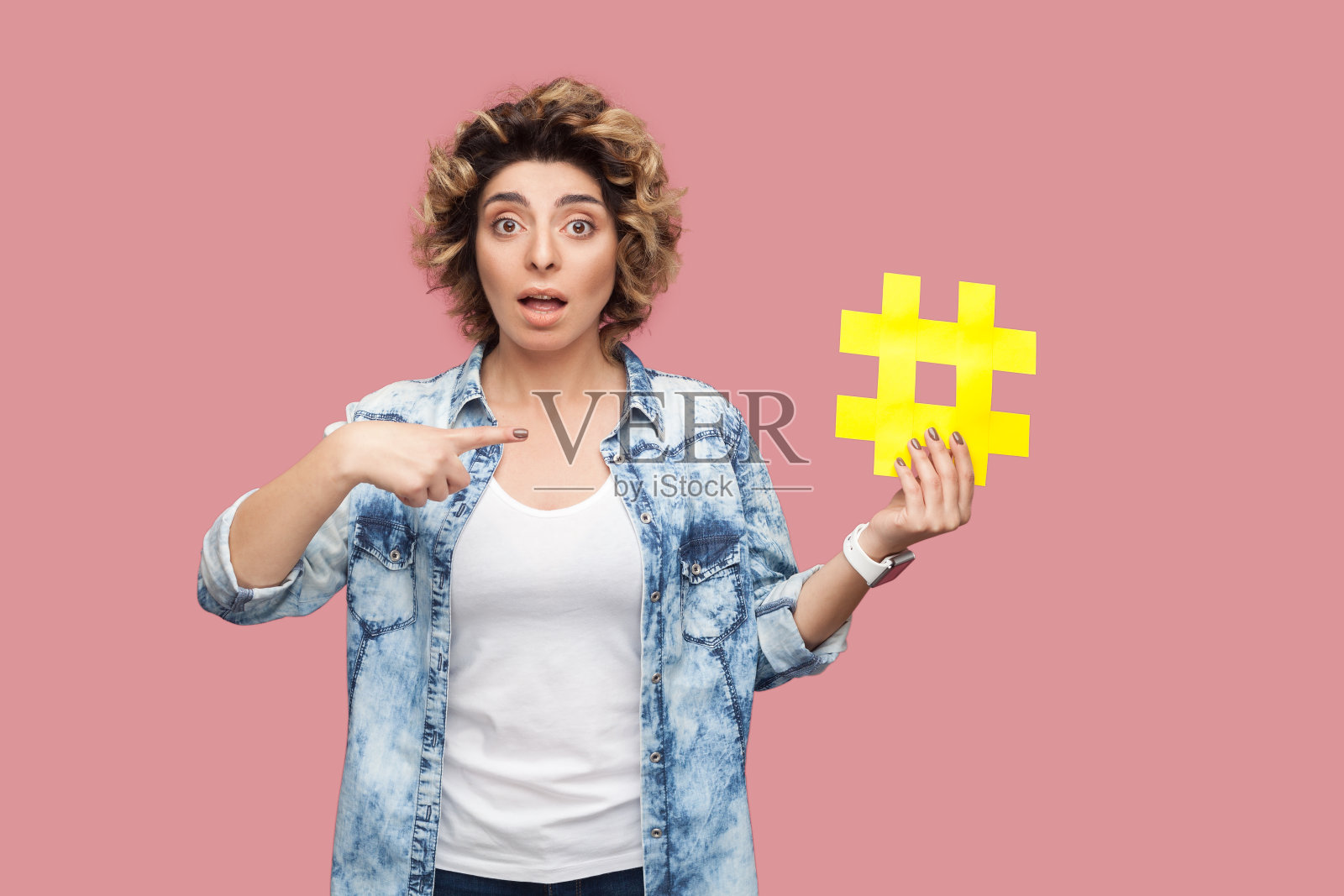 惊讶的漂亮女人站着指向黄色标签照片摄影图片