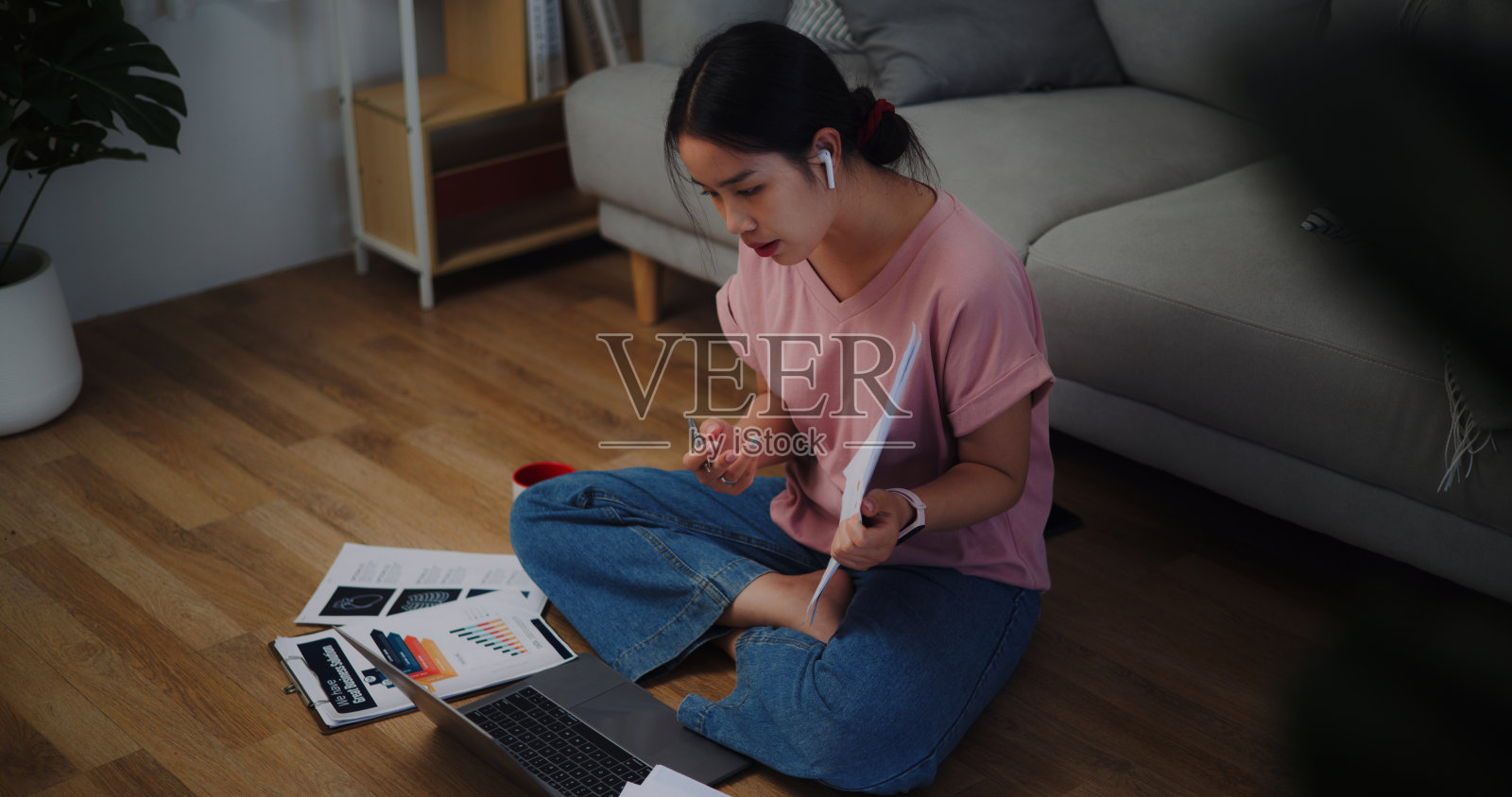 年轻女子坐在地板上用笔记本电脑在家里工作。照片摄影图片