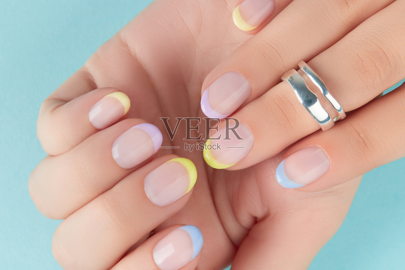 特写:修剪整齐的女人的手放在蓝色的背景上照片摄影图片