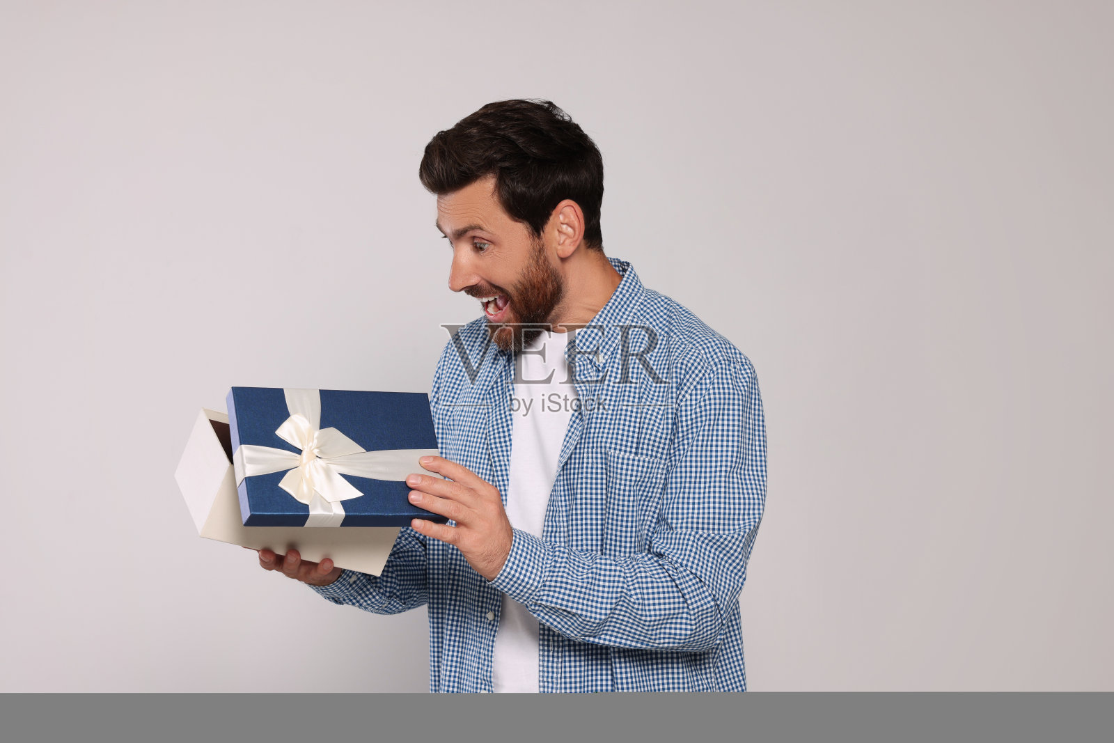 情绪化的男人打开礼盒浅灰色背景照片摄影图片
