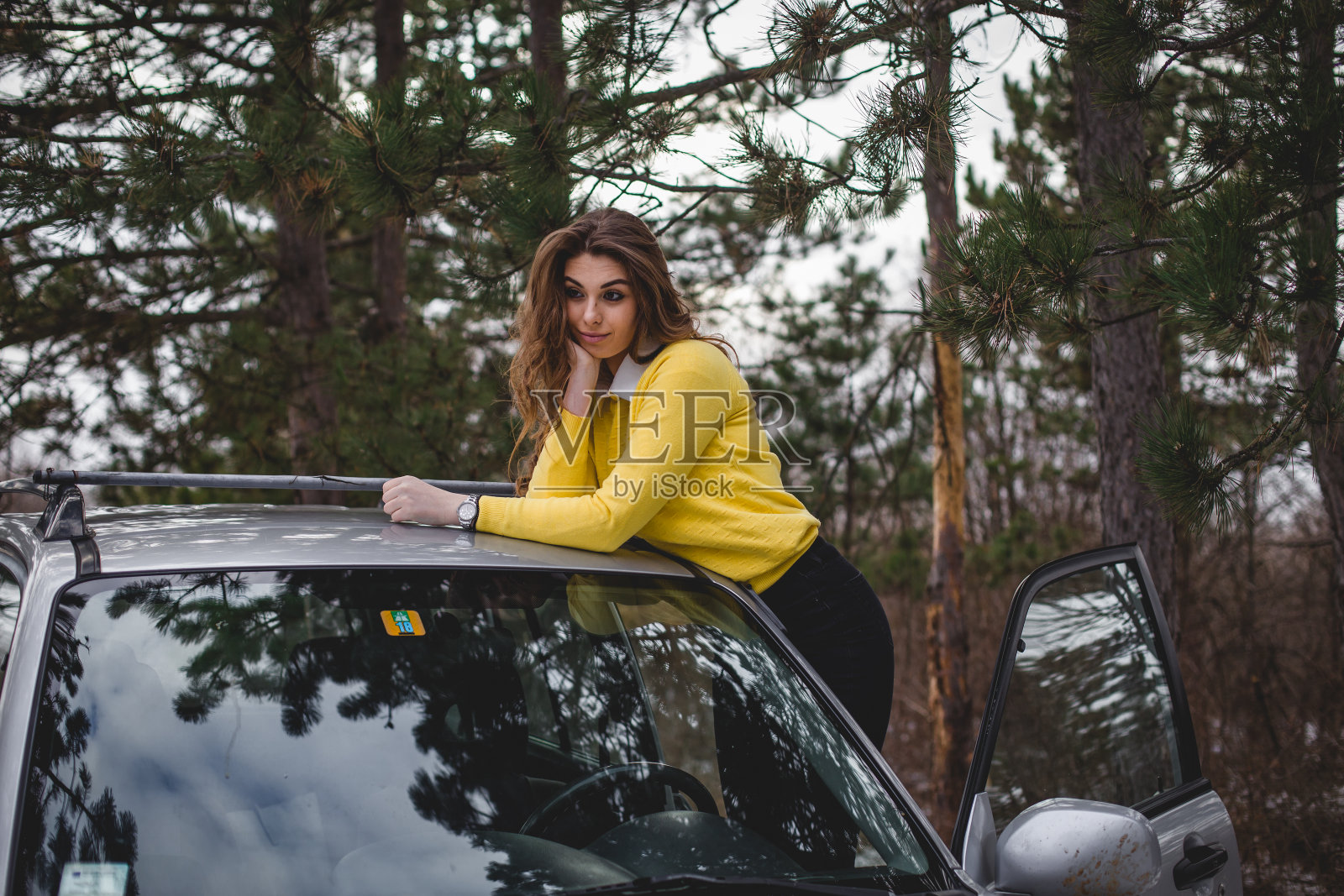 一名年轻女子在松树林中与她的越野车合影照片摄影图片