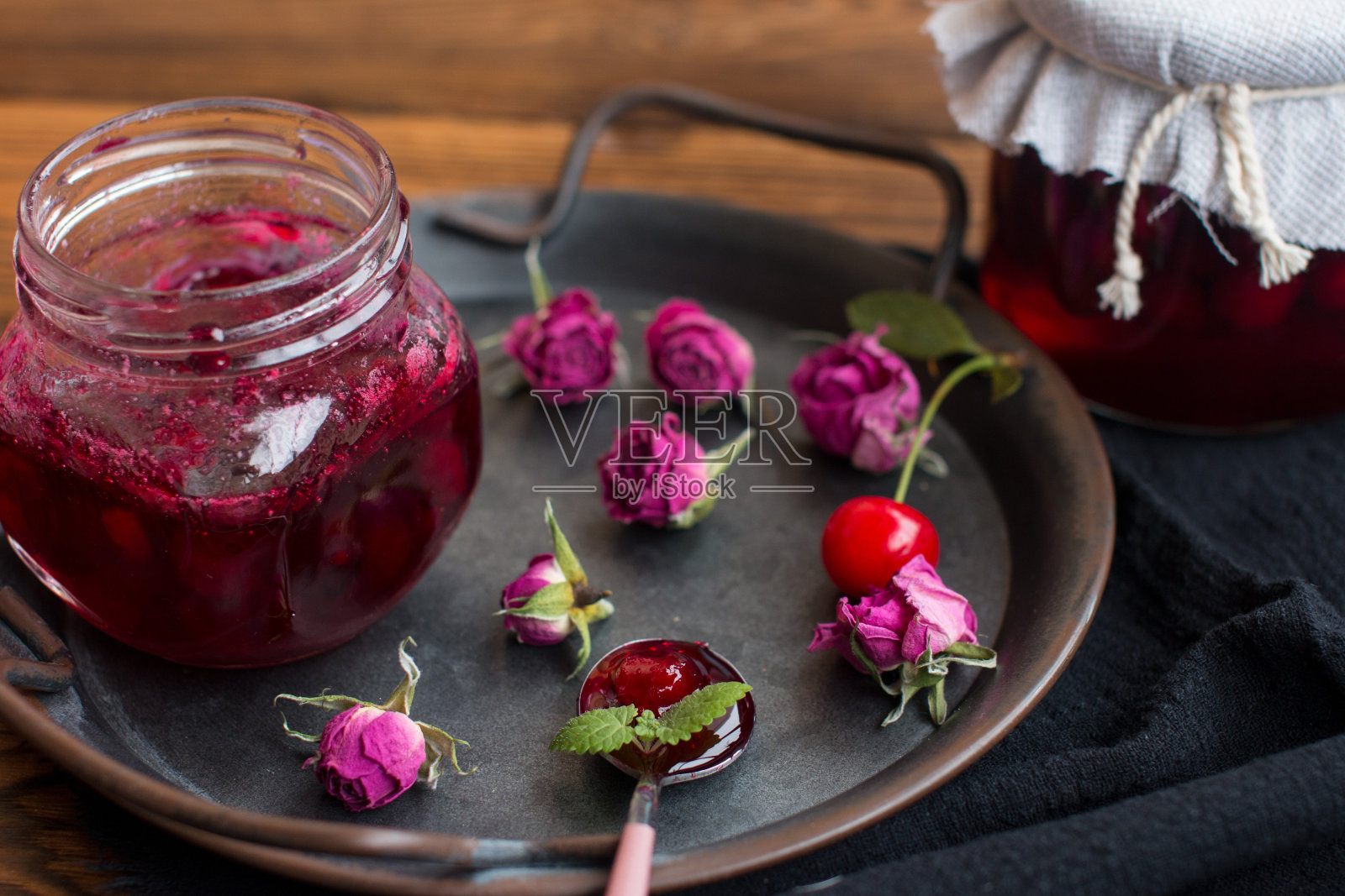 樱桃果酱在一个罐子里。在木质背景上收获红浆果照片摄影图片