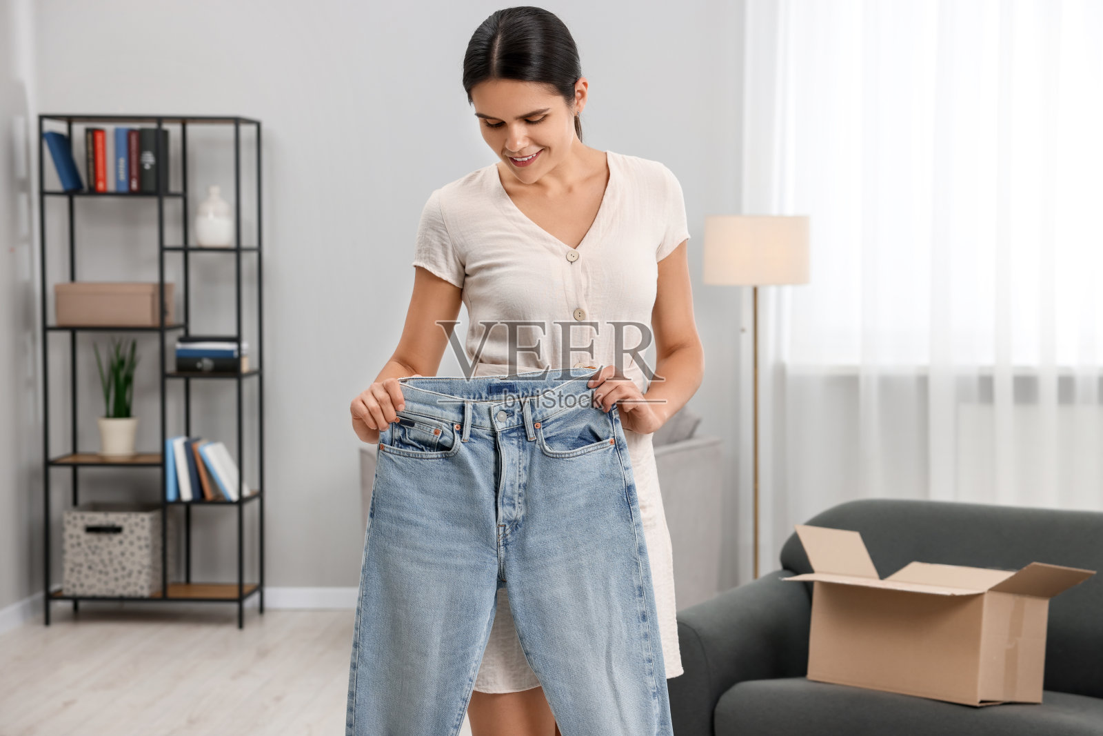 年轻女子刚在家里打开新牛仔裤。网上购物照片摄影图片