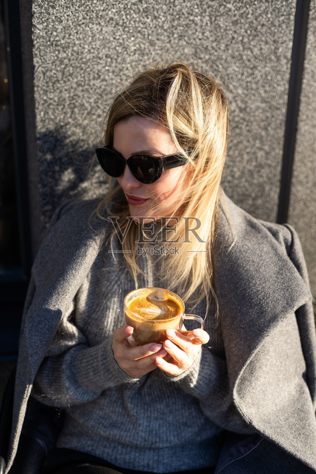 冷静时尚的成熟女人坐在外面的咖啡桌旁，端着一杯咖啡照片摄影图片