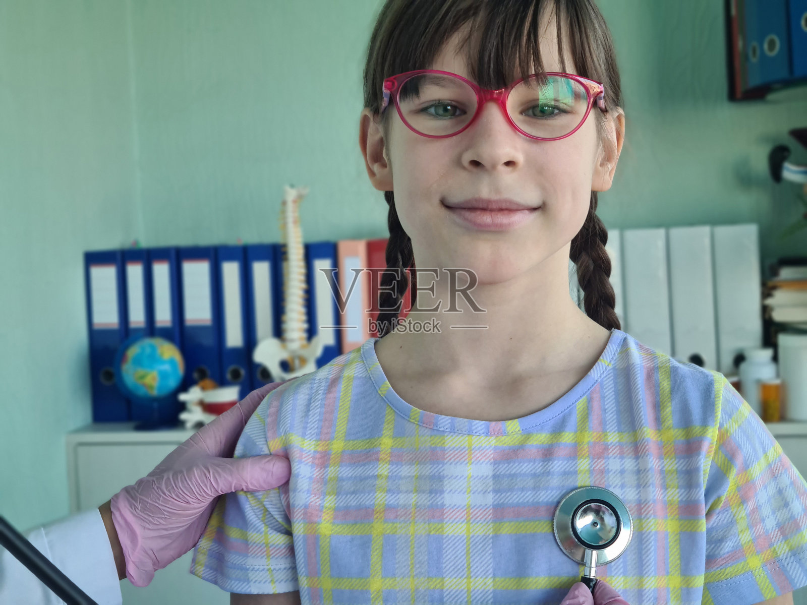 医生用听诊器检查一个女学生照片摄影图片