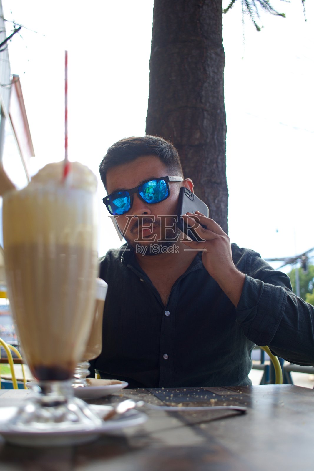 一个拉丁人在城市的露天咖啡店里打电话照片摄影图片