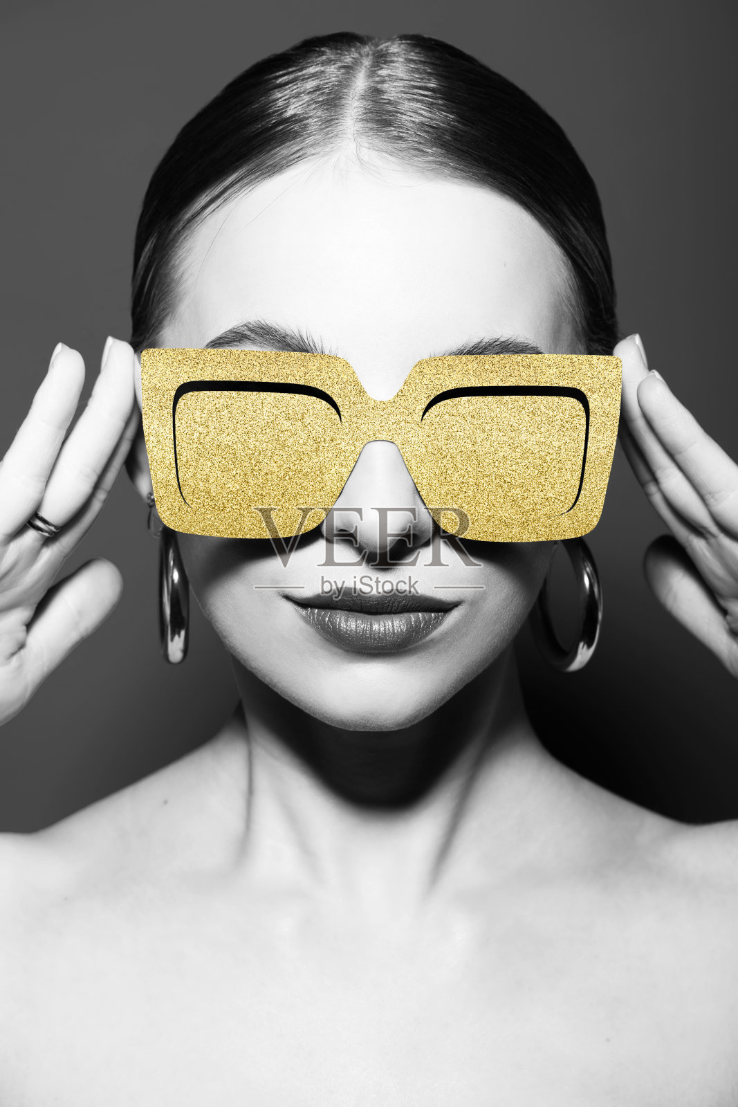 女性肖像与经典发型和金色复古太阳镜在灰色背景照片摄影图片