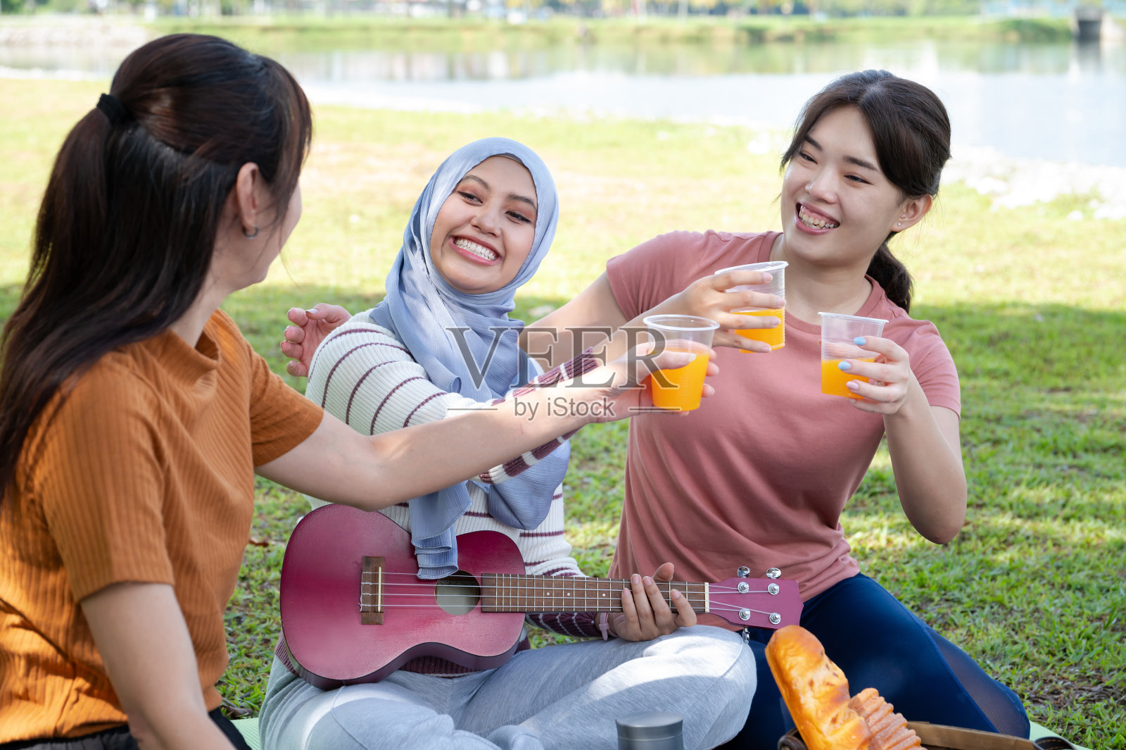 周末早上，一群微笑的多种族女性朋友在湖边花园野餐照片摄影图片