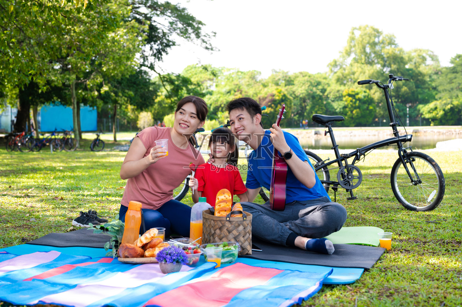 年轻的亚洲家庭在湖花园野餐照片摄影图片