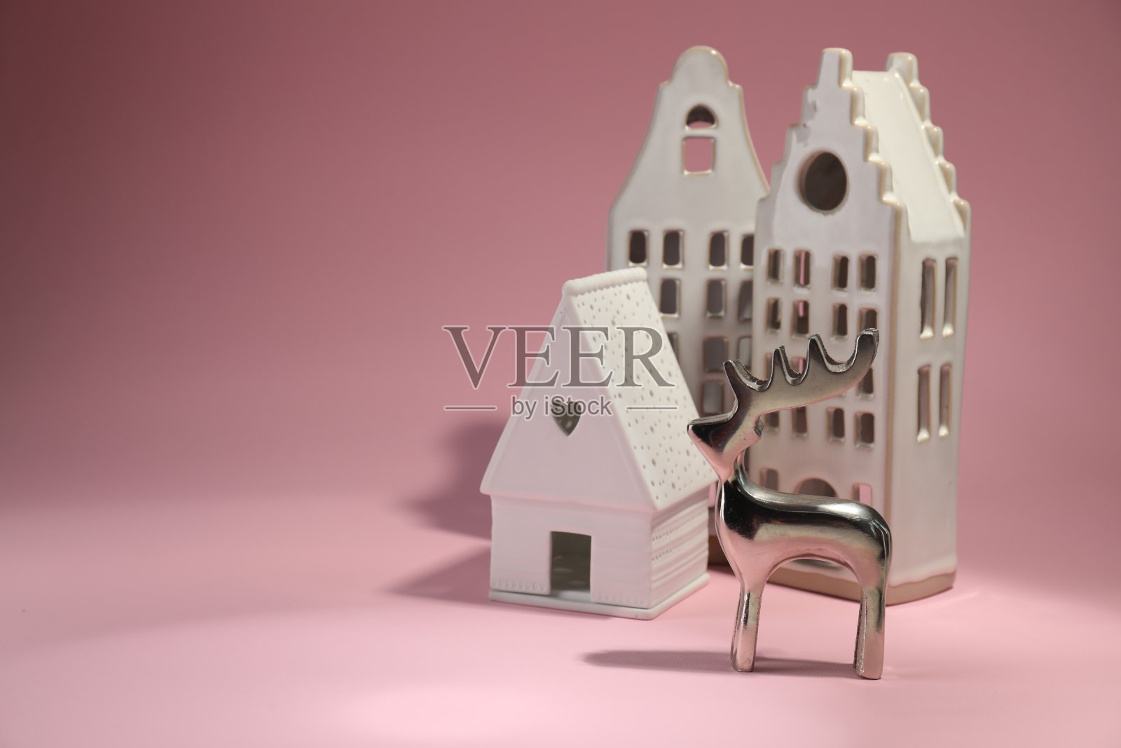 房子形状的烛台和银鹿在粉红色的背景，文字的空间照片摄影图片