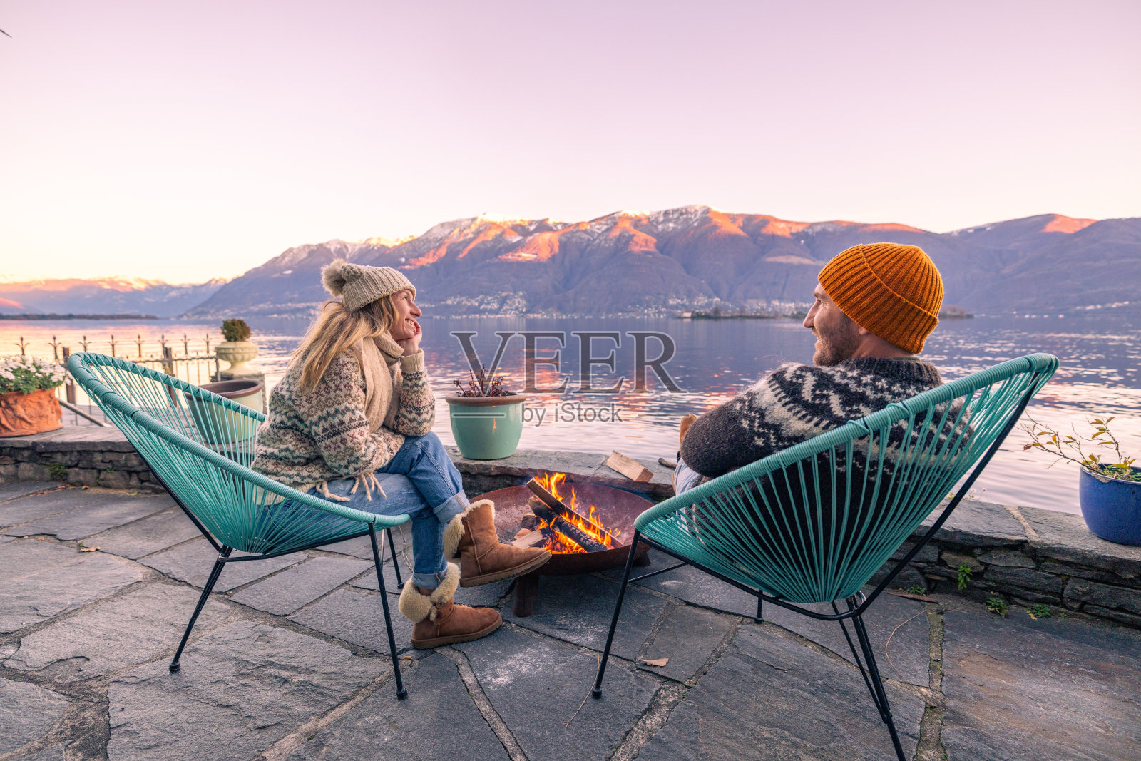 一对夫妇坐在花园的火炉旁，周围是大自然、湖泊和山景照片摄影图片