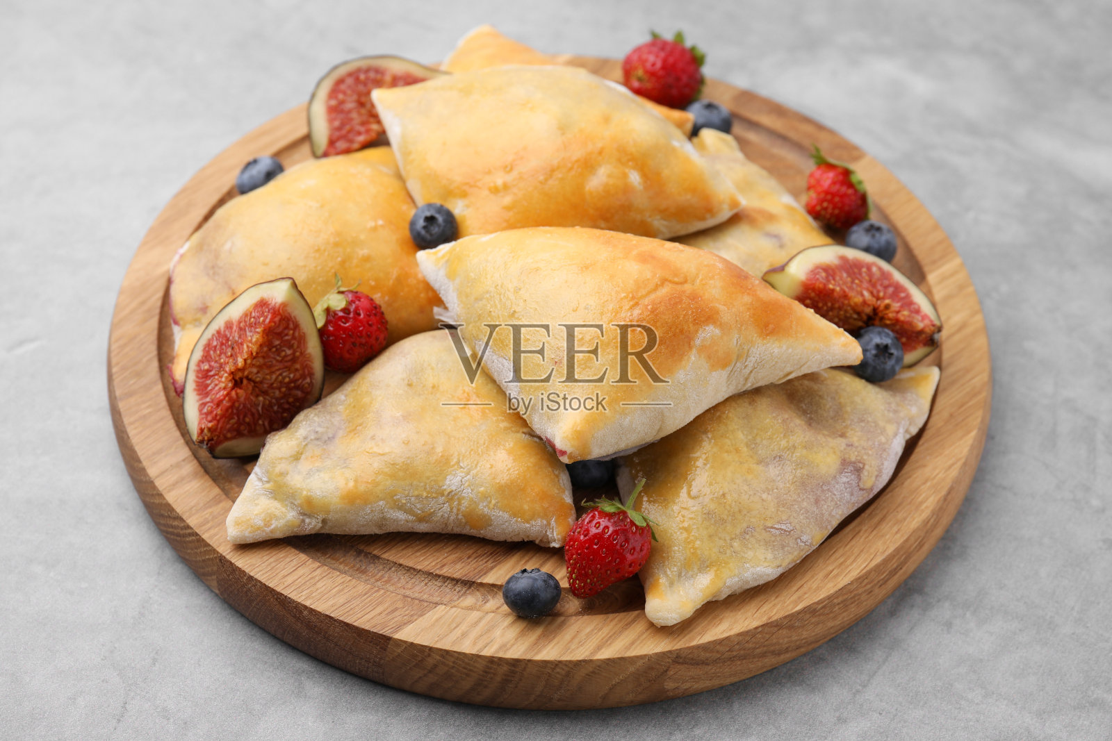 灰色桌子上美味的无花果和浆果萨莫萨，特写照片摄影图片