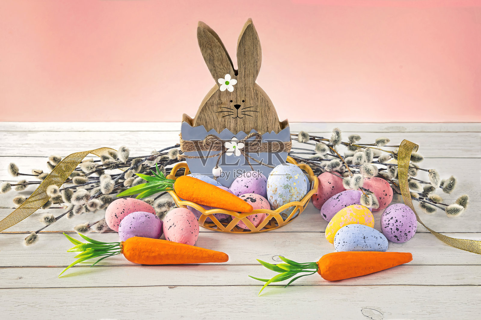 有复活节彩蛋、胡萝卜、柳树和黄丝带的复活节兔子。照片摄影图片