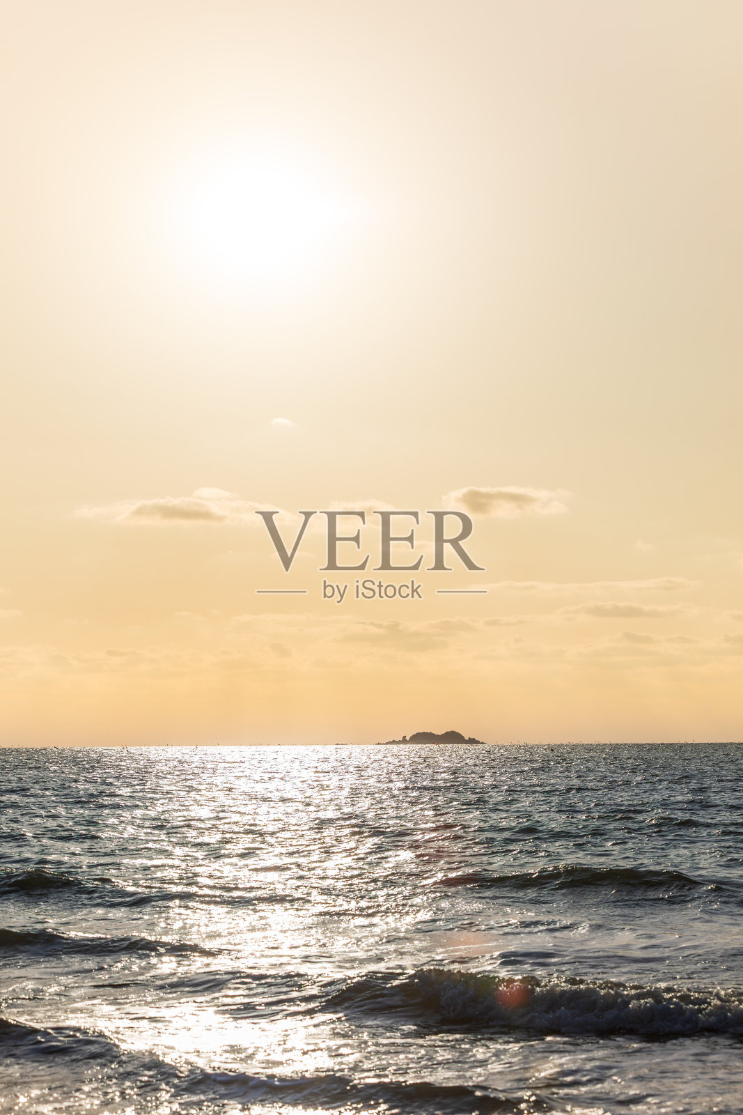 橙色的夕阳景观在海上。在地平线上可以看到一个小岛。照片摄影图片