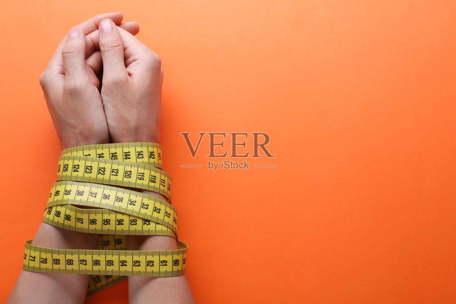 女人用卷尺绑在橙色背景上，俯视图和文字空间。饮食概念照片摄影图片