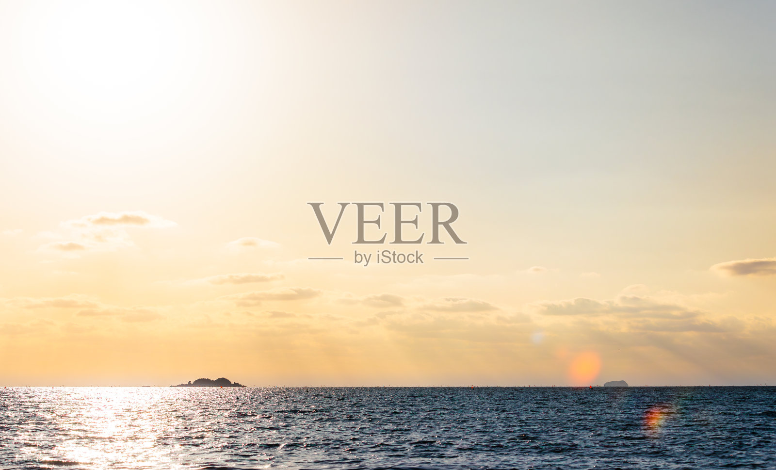 橙色的夕阳景观在海上。在地平线上可以看到一个小岛。照片摄影图片