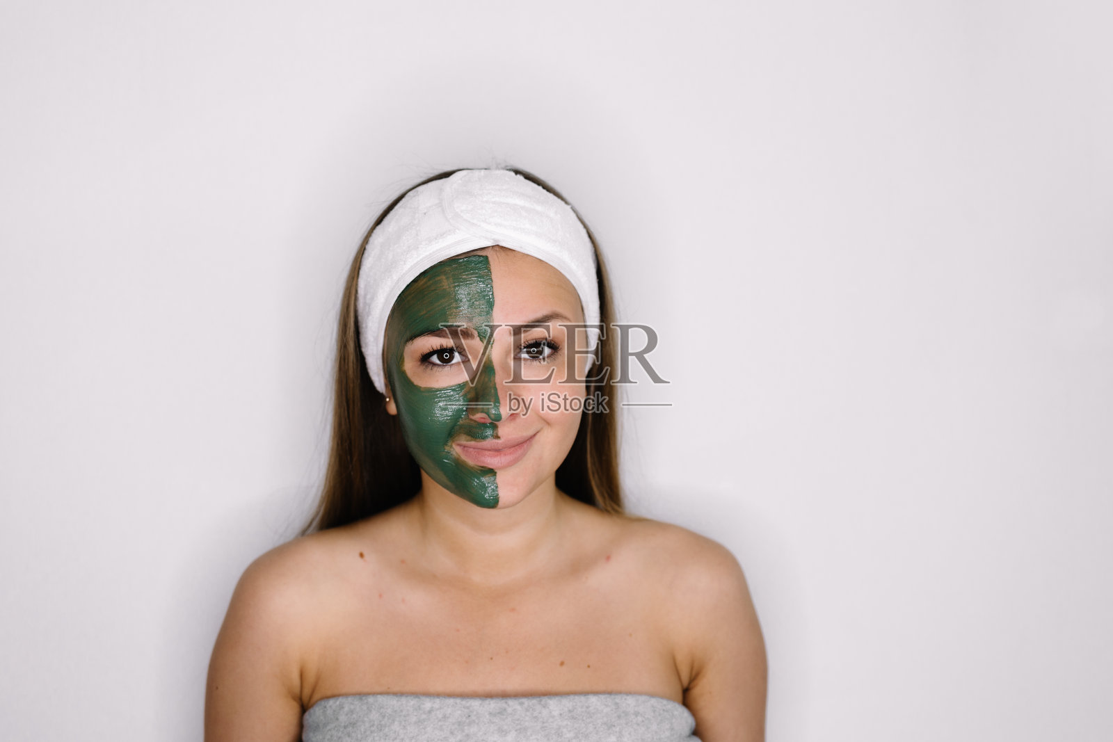 一位女士在半张脸上涂了提拉面霜，孤立在白色上照片摄影图片